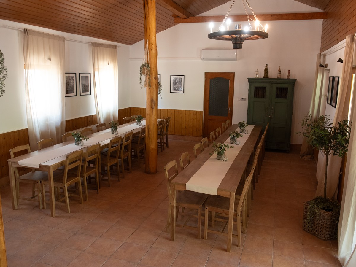 A rendezvényterem két hosszú, megterített asztallal és kovácsoltvas csillárral.